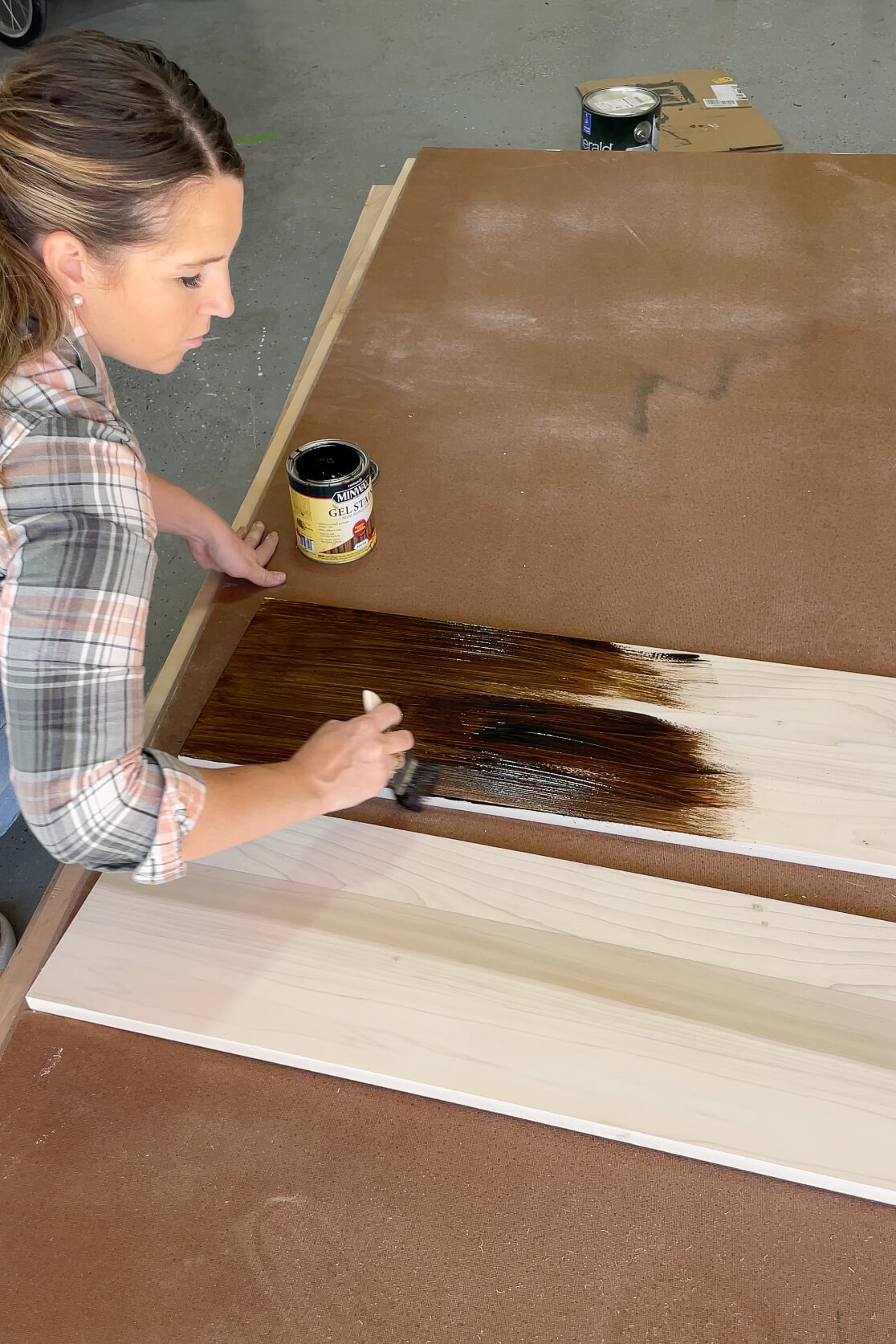 Applying stain to a wood shelf using a paintbrush. 